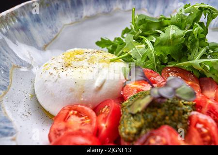 Burrata con rucola, pomodori ciliegini e salsa di pesto Foto Stock