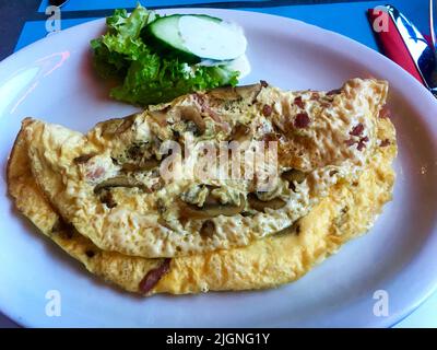 La colazione è un re. Deliziosa colazione al mattino con omelette di pancetta a dadini, funghi e prosciutto con pane tostato burro e marmellata. Foto Stock