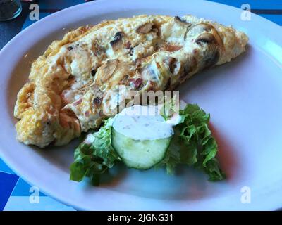 La colazione è un re. Deliziosa colazione al mattino con omelette di pancetta a dadini, funghi e prosciutto con pane tostato burro e marmellata. Foto Stock