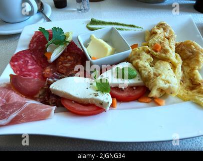 La colazione è un re. Delizioso pasto mattutino per iniziare la giornata. Uova strapazzate, lato soleggiato o frittata con sottili fette di pancetta di carne fredda, salame e prosciutto. Foto Stock