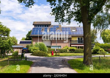 De Glindd Barneveld, Paesi Bassi - Luglio 2 2022: Casa moderna a coutnryside con pannelli solari, auto elettrica Tesla e stand con miele locale a De Glindd Barneveld in Gelderland Paesi Bassi Foto Stock