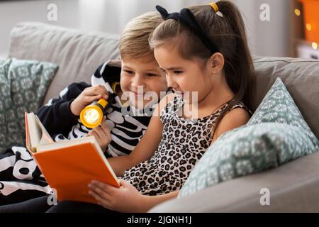 bambini in costumi di halloween lettura libro a casa Foto Stock