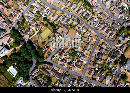 Una vista aerea direttamente sopra una comunità suburbana alla periferia di una città con strade e quartieri intrecanti Foto Stock