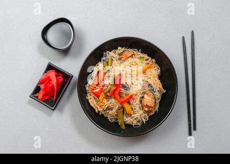 Spaghetti di vetro con verdure in una ciotola nera su sfondo grigio. Cucina Asiatica Asiatica. Tagliatelle asiatiche o Szechuan. Foto Stock