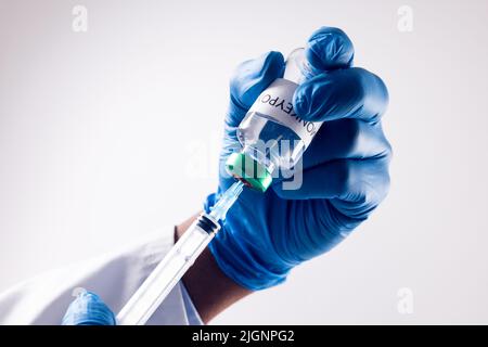 Mani del medico che tiene il flaconcino con il virus della scimmia e la siringa Foto Stock