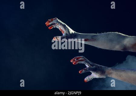 Composizione delle mani ricoperte di sangue e fumo su sfondo nero Foto Stock