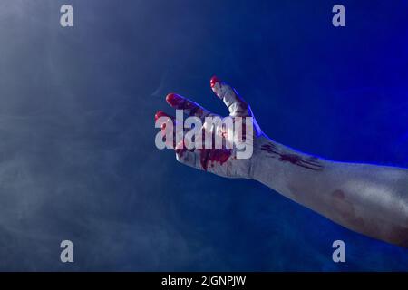 Composizione della mano ricoperta di sangue e fumo su sfondo nero Foto Stock