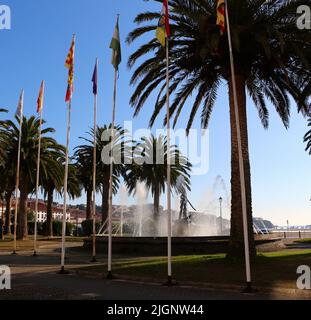 Fontana con una grande ancora e una fila di pali di bandiera San Vicente de la Barquera Cantabria Spagna Foto Stock