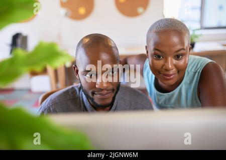 Due colleghi neri guardano lo schermo di un computer in un ufficio creativo Foto Stock