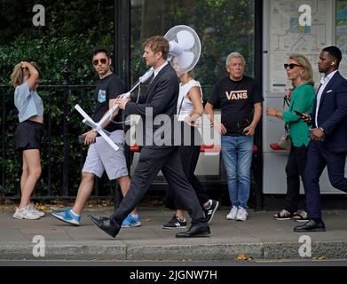 Un lavoratore d'ufficio porta un grande fan attraverso Westminster, centro di Londra. L'ufficio MET ha emesso un avvertimento di colore ambra per il surriscaldamento eccessivo in alcune parti del Regno Unito, prima che questa settimana si innalzano ulteriormente le temperature. Data foto: Martedì 12 luglio 2022. Foto Stock