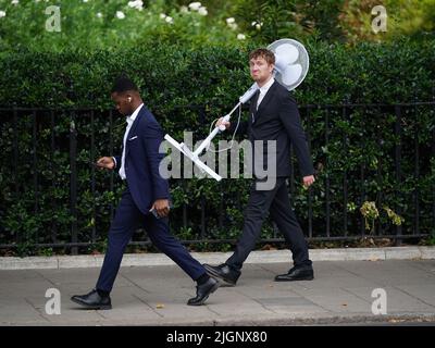 Un lavoratore d'ufficio porta un grande fan attraverso Westminster, centro di Londra. L'ufficio MET ha emesso un avvertimento di colore ambra per il surriscaldamento eccessivo in alcune parti del Regno Unito, prima che questa settimana si innalzano ulteriormente le temperature. Data foto: Martedì 12 luglio 2022. Foto Stock