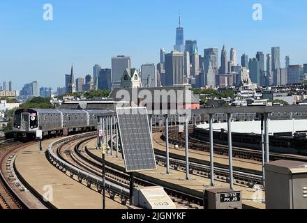 F linea ferroviaria che arriva alla stazione metropolitana di Smith Ninth Street con una vista chiara dello skyline di Lower Manhattan. Foto Stock