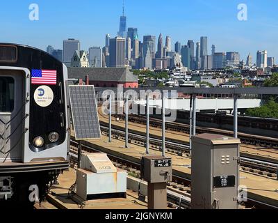 F linea ferroviaria che arriva alla stazione metropolitana di Smith Ninth Street con una vista chiara dello skyline di Lower Manhattan. Foto Stock