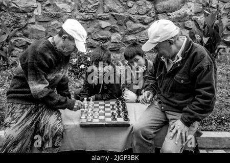 Due uomini che giocano a Scacchi guardati da bambini locali, Pisac, la Valle Sacra, Provincia di Calca, Perù. Foto Stock