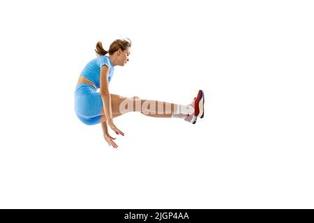 Tecnica a salto triplo. Studio di atleta femminile in sport uniforme salto isolato su sfondo bianco. Concetto di sport, azione, movimento, velocità. Foto Stock