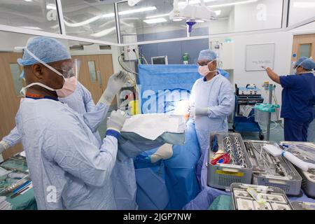 Un chirurgo e un personale NHS effettuano la chirurgia del ginocchio, anche nota come artroplastica, in un ospedale NHS. Foto Stock