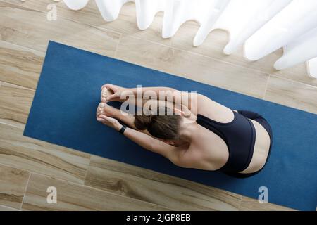 Giovane donna yoga che fa stretching durante la sua routine yoga mattina. Foto Stock