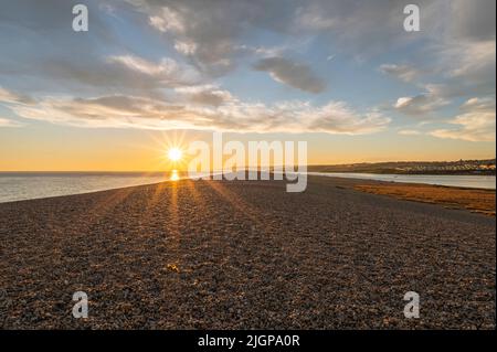 Tramonto sulla riva di ghiaia della spiaggia di Chesil parte della costa Jurassic, Dorset Foto Stock