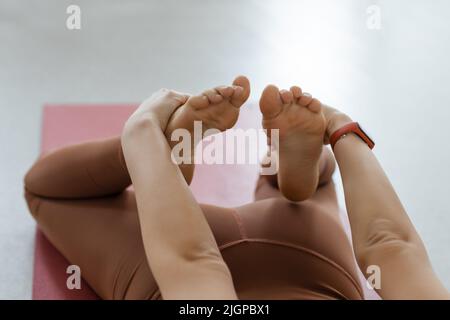 yoga asana attività deflessione sullo stomaco primo piano delle mani prese le gambe. Body Stretching Fitness e Pilates Foto Stock