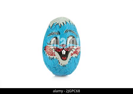 Un uovo di cioccolato avvolto in un foglio blu con faco isolato su sfondo bianco. Foto Stock