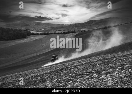 Trattore che aratura un campo. Toscana, Italia. Fotografia in bianco e nero. Foto Stock