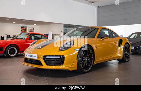 Un'immagine di una Porsche 911 Turbo S arancione all'interno di una concessionaria. Foto Stock