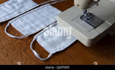 Una garza protettiva per il viso in prossimità di una macchina da cucire. Protezione di base contro coronavirus, COVID-19, infezioni e polvere a casa. Maschera facciale do-it-yourself a casa. Foto Stock