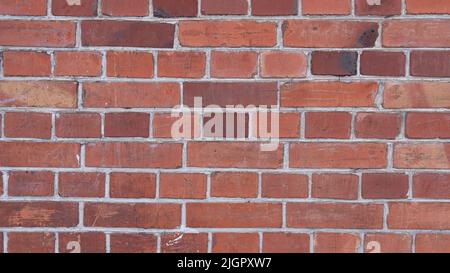 Vintage graffiato muro di mattoni rossi. Sfondo in mattoni testurizzati. La vista panoramica della parete vuota con spazio di copia può essere utilizzata per la progettazione di interni. Foto Stock