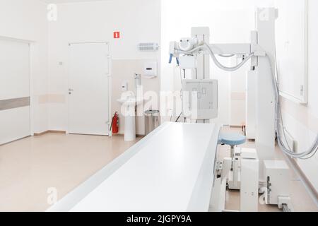 Reparto raggi X in ospedale moderno. Sala di radiologia con macchina di scansione con letto vuoto. Tecnico che regola una macchina a raggi X. Scansione torace, cuore Foto Stock