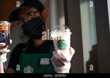 I lavoratori Starbucks consegnano gli ordini al drive-thru. Foto Stock