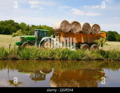 Caricamento di balle di fieno sul rimorchio nella campagna francese, Normandia, Francia, Europa Foto Stock