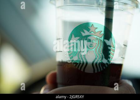 Una persona che tiene una tazza di caffè Starbucks in auto. Foto Stock