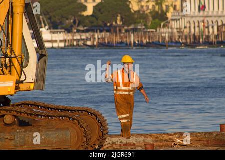 VENEZIA, ITALIA - 20 APRILE 2019 traffico della Laguna Veneziana - uomo di lavoro con elmetto sul lato del canale Foto Stock