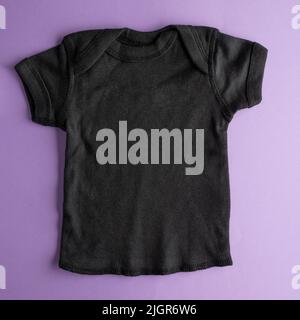 Mockup piatto di t-shirt in cotone nero per bambini per ragazzi e ragazze su sfondo viola. Layout per la progettazione e la collocazione di pubblicità, loghi, Foto Stock
