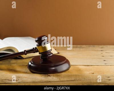 Giudizio e giustizia. Gavel del giudice su un tavolo di legno e un libro aperto su sfondo beige. Stato di diritto, processo equo, costituzione, presunzione di in Foto Stock