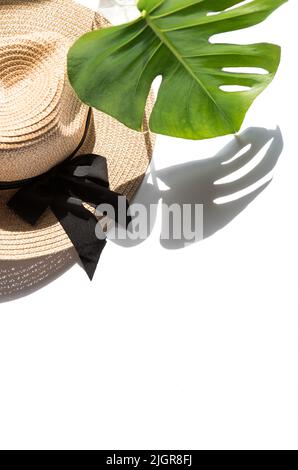 Modello piatto estivo. Cappello di paglia e ombra di foglia monstera Foto Stock