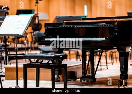 Un pianoforte sul palco della Filarmonica tra gli altri strumenti musicali Foto Stock