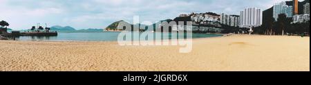 Uno scatto panoramico della spiaggia sabbiosa sulla baia di Repulse con edifici e grattacieli sullo sfondo Foto Stock