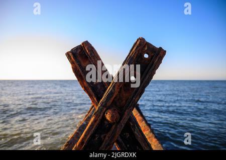 Un primo piano di pezzi di metallo arrugginito sul mare in Aberaeron Breakwater Foto Stock