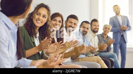 Gli uomini d'affari applaudono l'allenatore femminile ringraziandola per l'interessante conferenza aziendale. Foto Stock