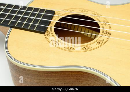 Corpo in ukulele acustico di legno giallo con buco sonoro e archi su sfondo bianco studio. Primo piano del risonatore. Chitarra classica d'epoca. Foto Stock