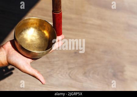L'uomo mani usando la ciotola di canto nella terapia healing del suono all'aperto, primo piano. Foto Stock