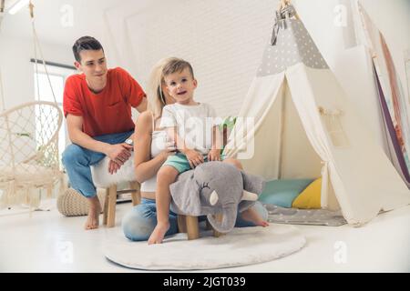 famiglia felice che gioca in frontof la tenda nel soggiorno, concetto di famiglia. Foto di alta qualità Foto Stock