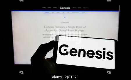 Persona che tiene il cellulare con il logo della società americana cripto Genesis Global Trading Inc. Sullo schermo di fronte al sito web. Mettere a fuoco sul display del telefono. Foto Stock
