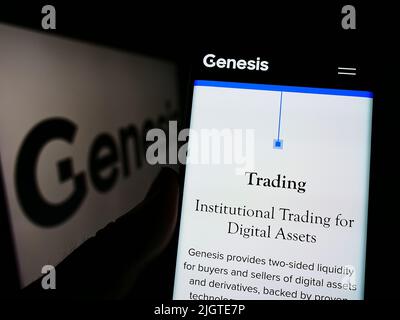 Persona con smartphone e sito web della società di crittografia statunitense Genesis Global Trading Inc. Su schermo con logo. Concentrarsi sul centro del display del telefono. Foto Stock