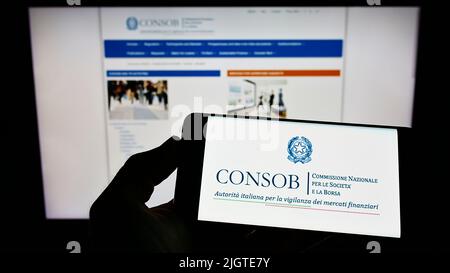 Persona con cellulare con logo di Commissione Nazionale per le Societa e la Borsa (CONSOB) su schermo con pagina web. Mettere a fuoco sul display del telefono. Foto Stock