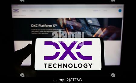 Persona che tiene smartphone con logo della società di consulenza IT statunitense DXC Technology Company sullo schermo di fronte al sito Web. Mettere a fuoco sul display del telefono. Foto Stock