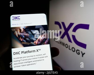Persona che tiene smartphone con pagina web della società di consulenza IT statunitense DXC Technology Company sullo schermo con logo. Concentrarsi sul centro del display del telefono. Foto Stock