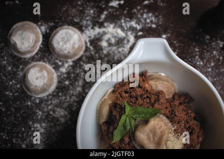 Pasta madre sana grandi ravioli (aka sorrentinos) su un tavolo di legno infarinato. Una moderna rivisita di un piatto di cucina italiana tradizionale. Foto Stock