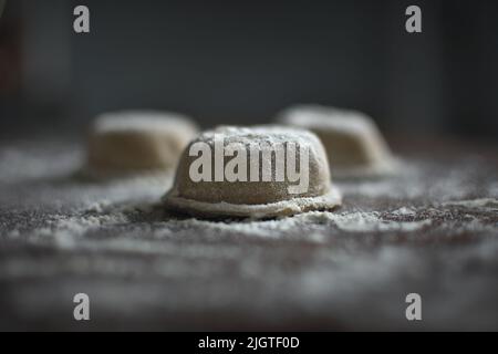 Pasta madre sana grandi ravioli (aka sorrentinos) su un tavolo di legno infarinato. Una moderna rivisita di un piatto di cucina italiana tradizionale. Foto Stock